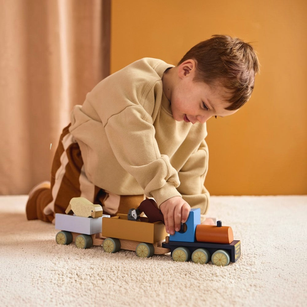 aelgmark 北歐生活選物 Kid’s Concept 木製農場動物小火車，幼兒正在地毯上推動色彩繽紛的火車玩具，包含可拆卸的動物積木與貨車。