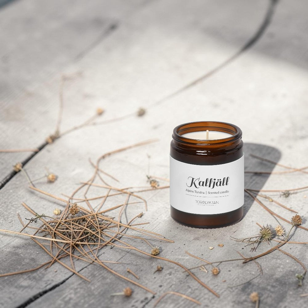 aelgmark Alpine Tundra scented candle in amber glass jar with white label, notes of juniper and rosemary.