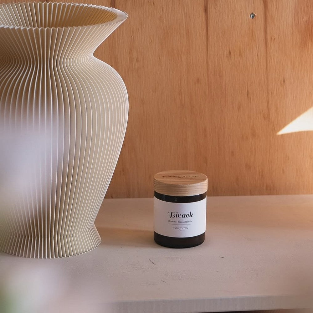 aelgmark Bivack scented candle with cinnamon and blackberry notes in a dark glass jar with wooden lid.