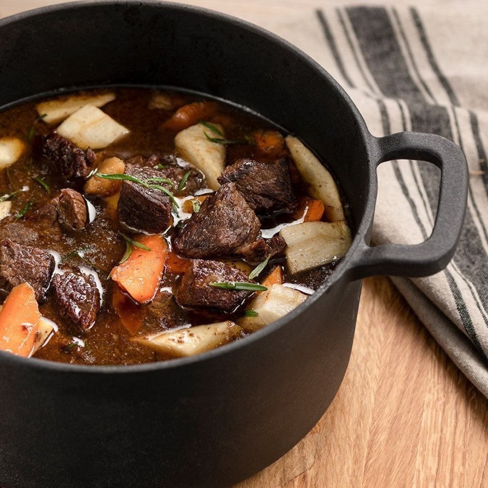aelgmark black cast iron Dutch oven filled with hearty stew, featuring tender beef chunks, root vegetables, and herbs.
