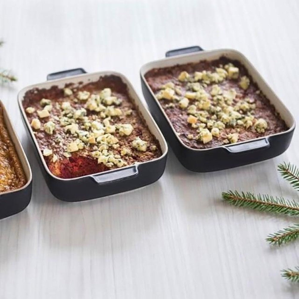 aelgmark black ceramic baking dish with handles, filled with a savory dish topped with cheese.