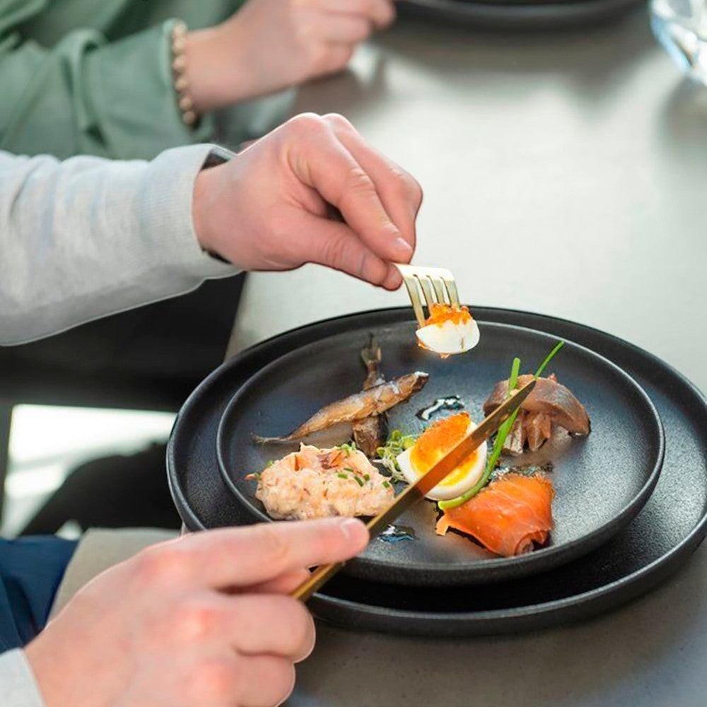 aelgmark black matte 26cm ceramic plate with food, including salmon, egg, and fish.