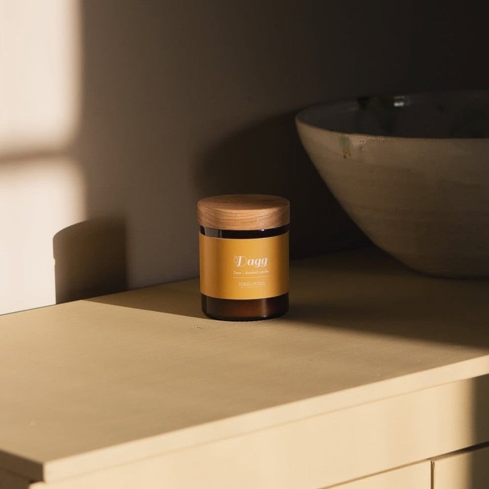 aelgmark Dew scented candle in amber glass jar with wooden lid, notes of pine needle, grapefruit, and lemon.