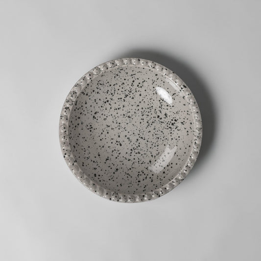Aelgmark Ditte 26cm stoneware deep plate in beige/grey with black speckle pattern and beaded rim.