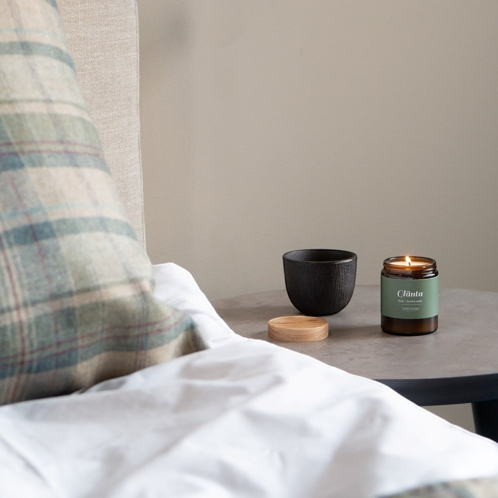 aelgmark Glade scented candle in amber glass jar with green label, featuring notes of cedarwood, vetiver, sandalwood, bergamot, apple, and cherry.