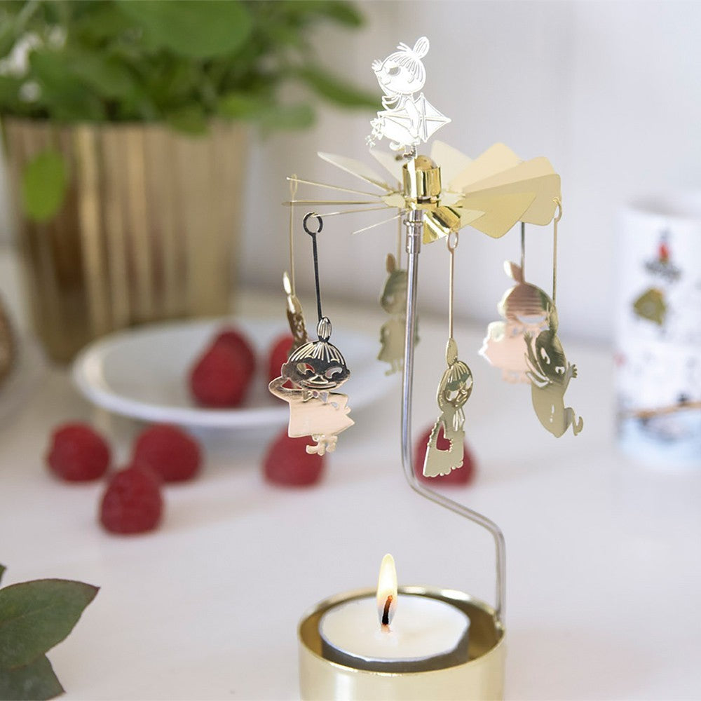 aelgmark gold spinning Moomin candle holder with dangling characters and a lit tea light, creating a festive atmosphere.