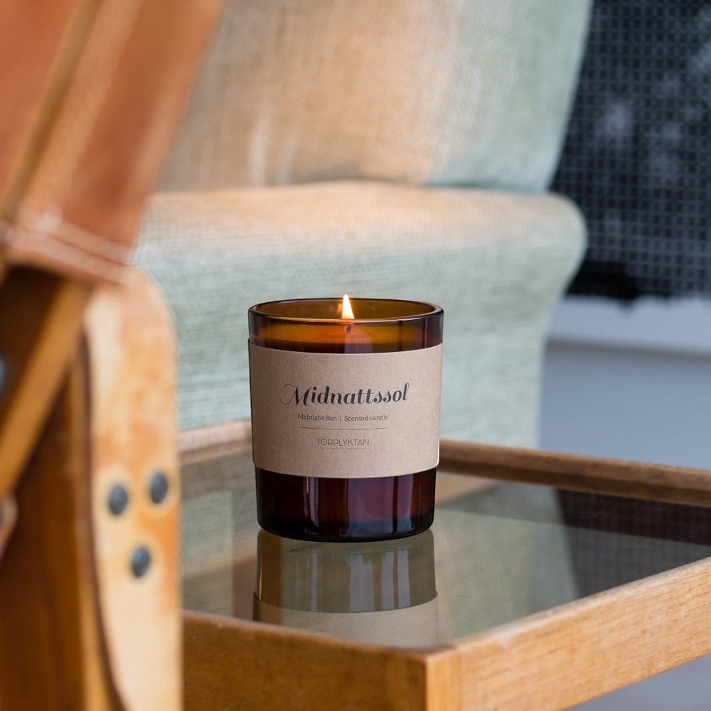 aelgmark北歐生活選物 Midnight Sun scented candle in amber glass jar with kraft paper label, burning.