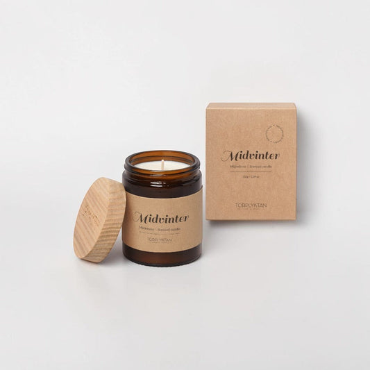 aelgmark Midwinter scented candle in amber glass jar with wooden lid, featuring sandalwood and vanilla notes.