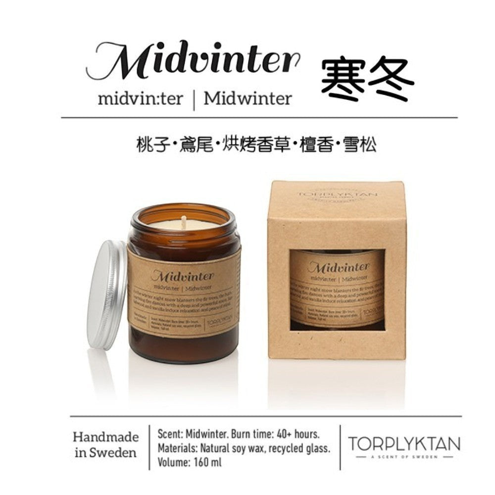 aelgmark Midwinter scented candle in amber glass with silver lid, featuring sandalwood, vanilla, and wood notes. Natural soy wax, handmade in Sweden.