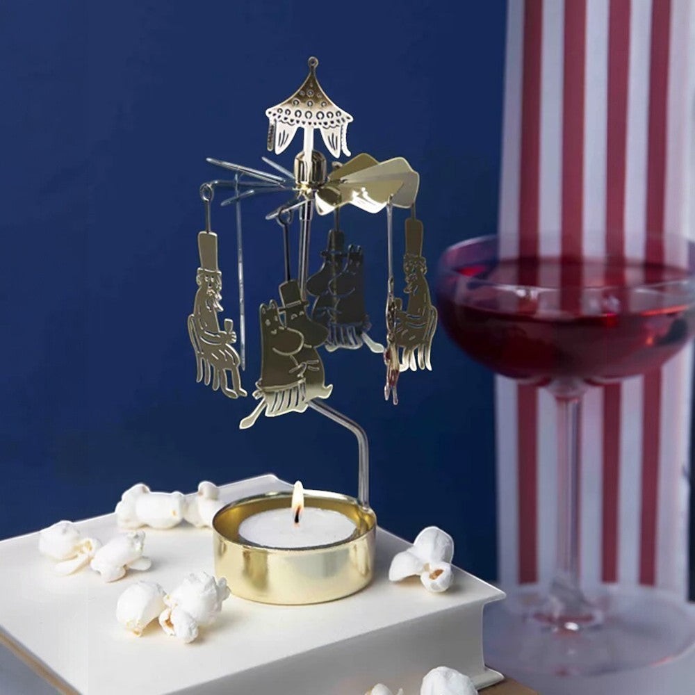 aelgmark Moomin party spinning tea light holder with golden finish and Moomin characters. Includes a lit tea light.