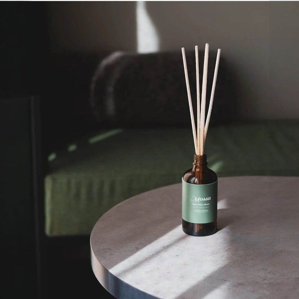 aelgmark Mossa reed diffuser with pine, patchouli, and cedarwood scents in a brown glass bottle with a green label.