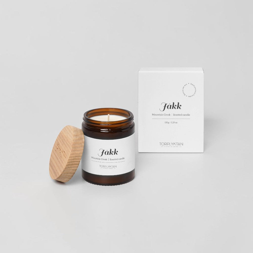 aelgmark Mountain Creek scented candle in amber glass jar with wooden lid, notes of watercress, dill, musk, and iris.