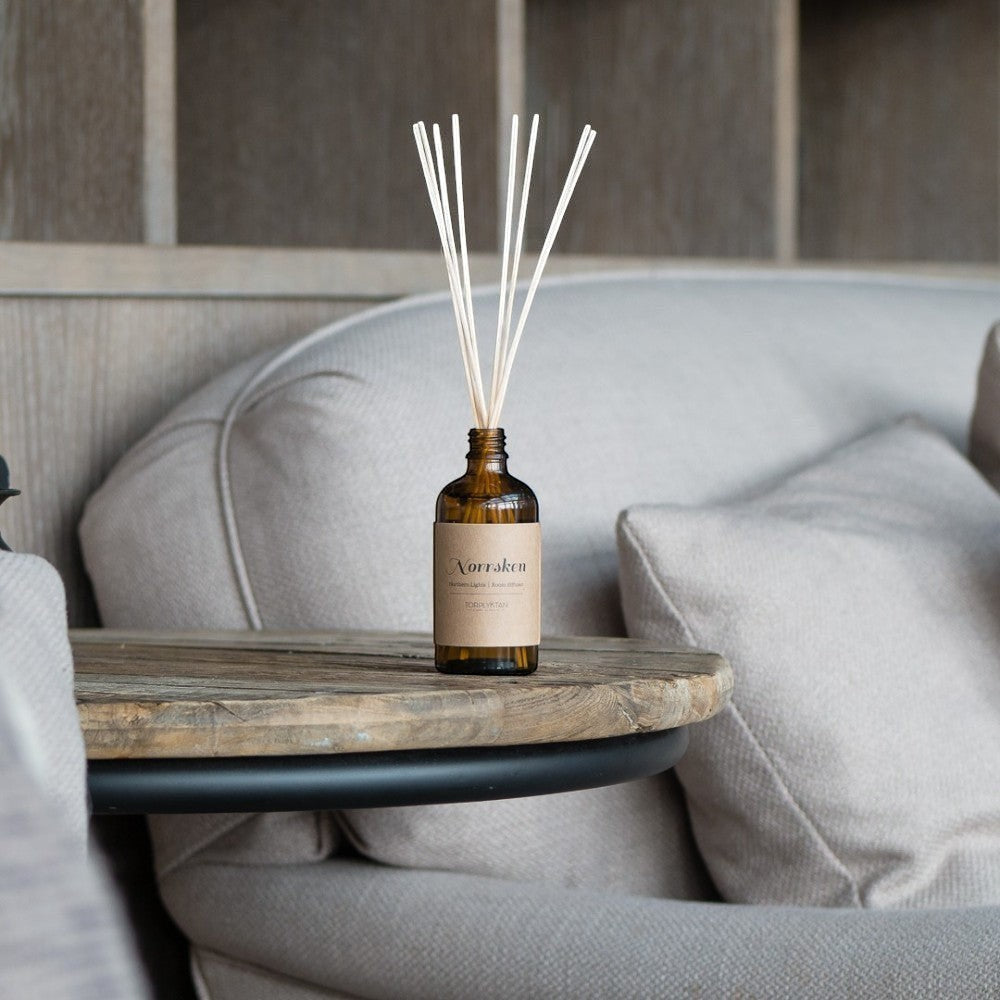 aelgmark Northern Lights reed diffuser in amber glass bottle with natural reeds, warm woody scent.