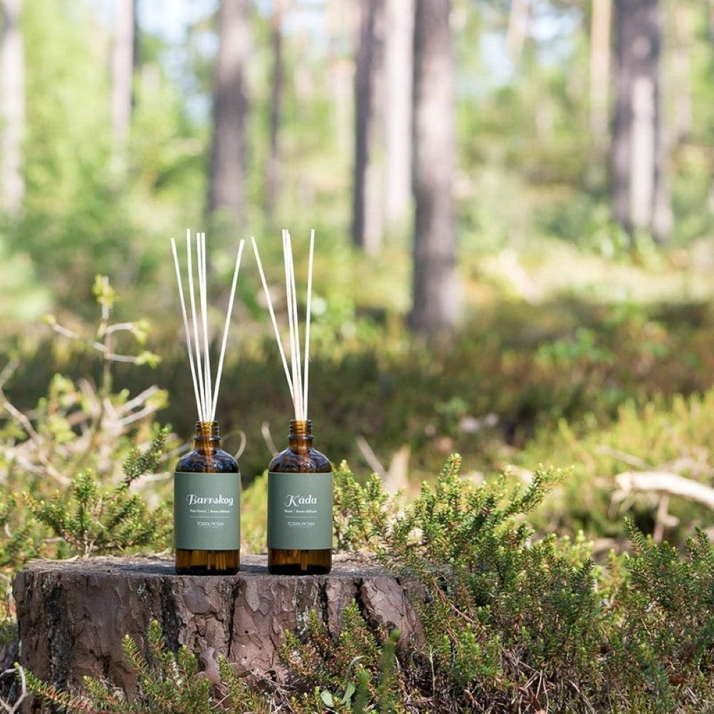 aelgmark Northern Woods Amber reed diffuser with pine, sandalwood, and frankincense notes in a brown glass bottle.