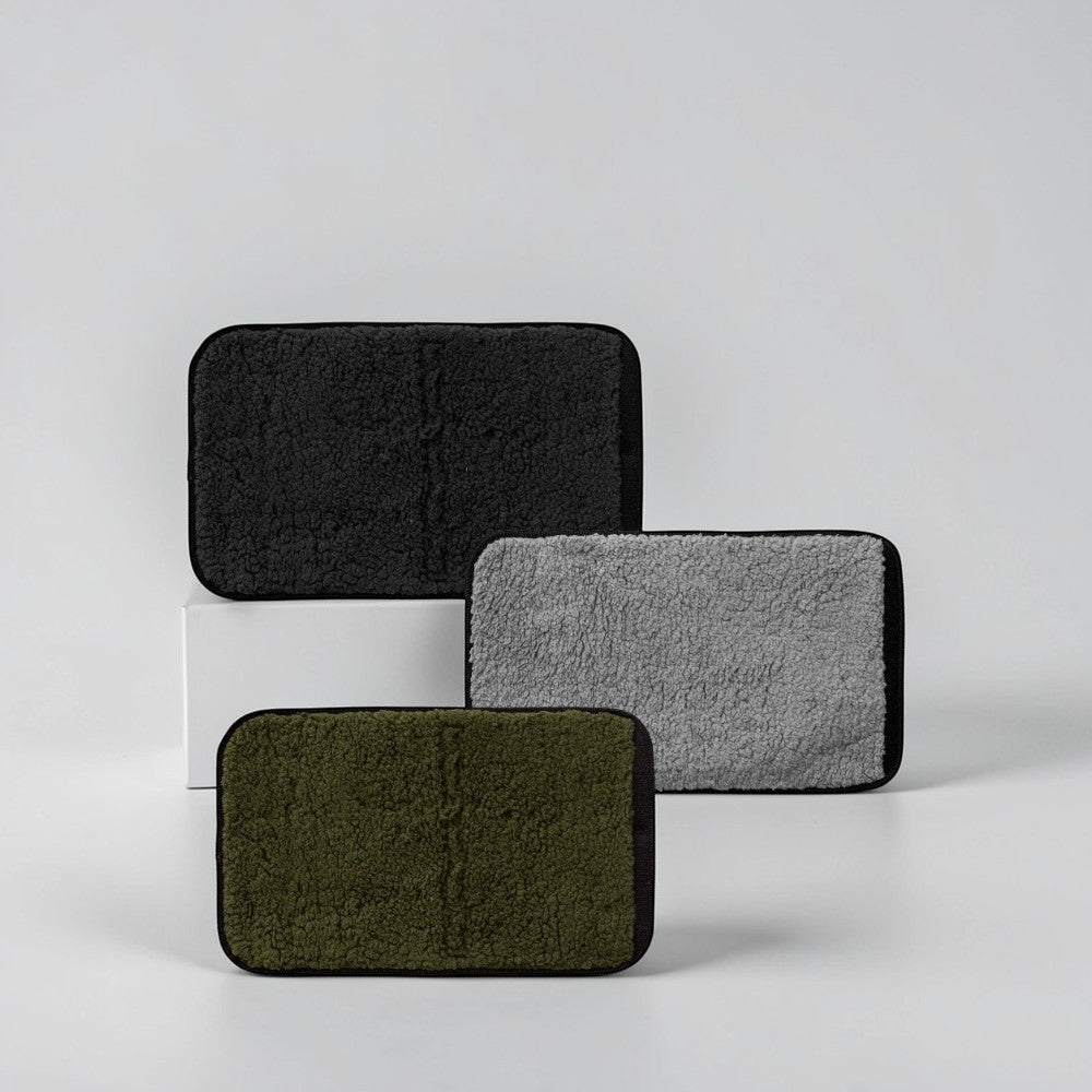 aelgmark outdoor seat cushion in black, grey, and olive green, made of faux shearling with waterproof backing.