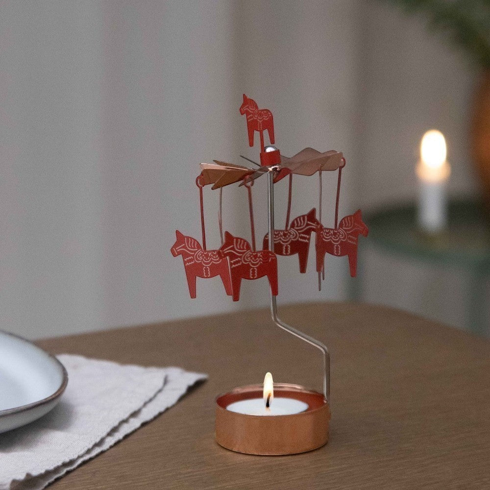 aelgmark red Dala horse carousel candle holder with spinning horses and a lit tea light.