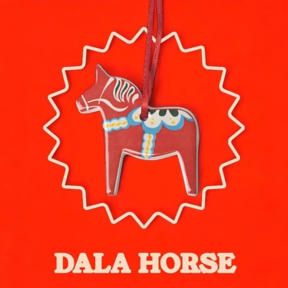 aelgmark red ceramic Dala horse ornament with white and blue painted details, hanging from a red ribbon.