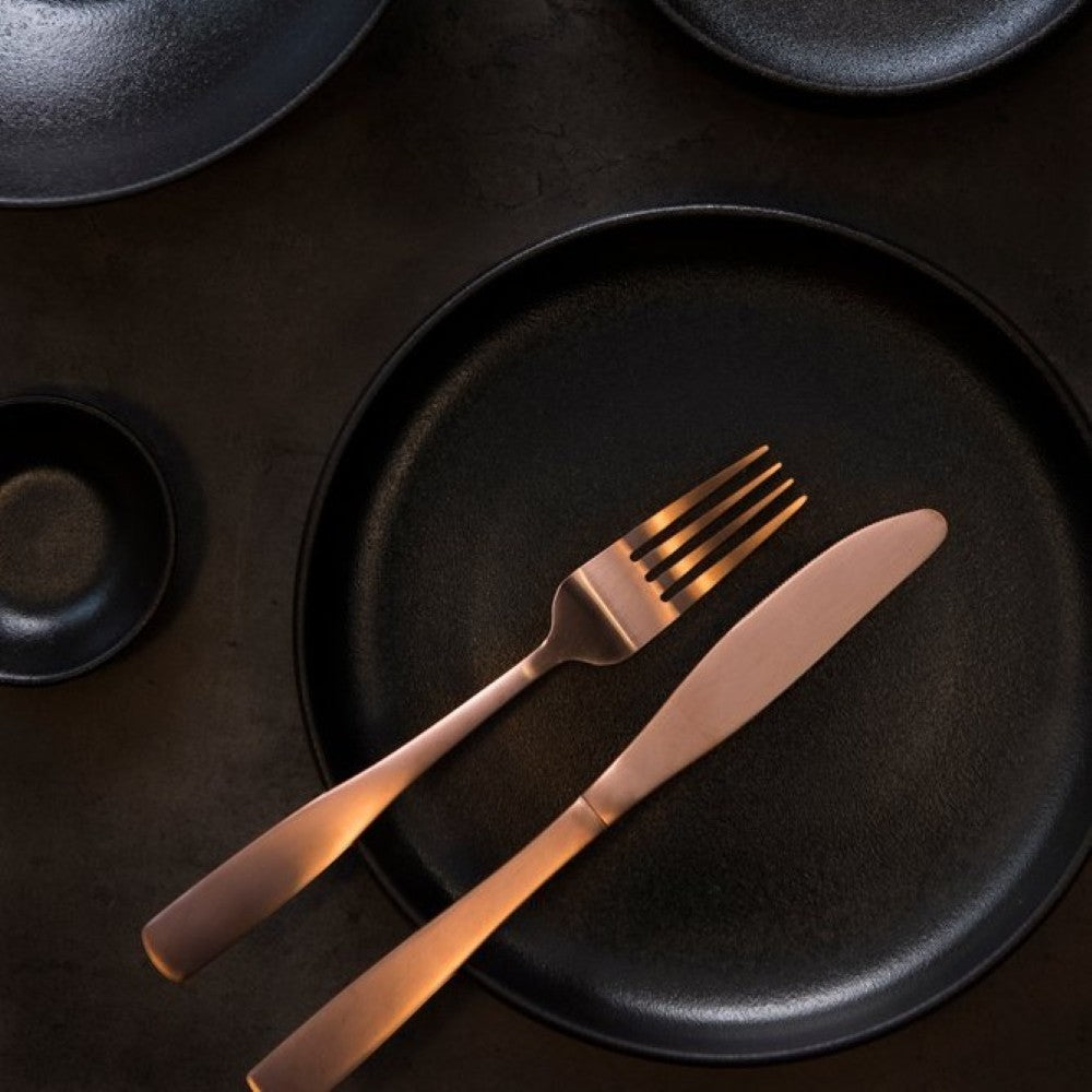 Aelgmark rose gold stainless steel cutlery set with PVD coating, including fork and knife, on a black plate.
