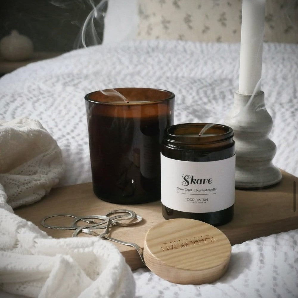 aelgmark Snow Crust scented candle in amber glass jar with wooden lid, notes of cinnamon, mint, bergamot.
