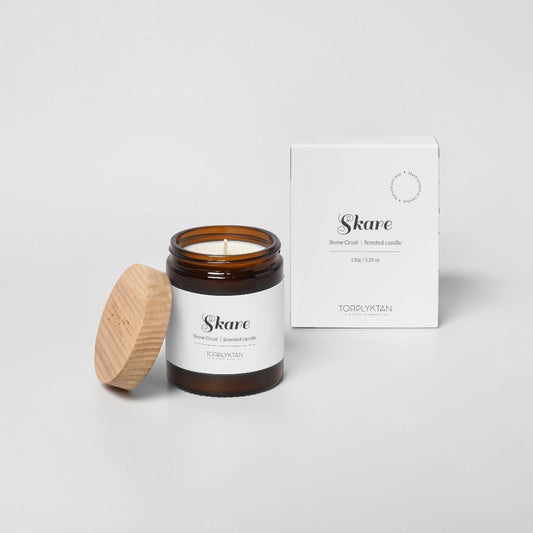 aelgmark Skare Snow Crust scented candle in amber glass jar with wooden lid. Notes of cinnamon, mint, and bergamot.