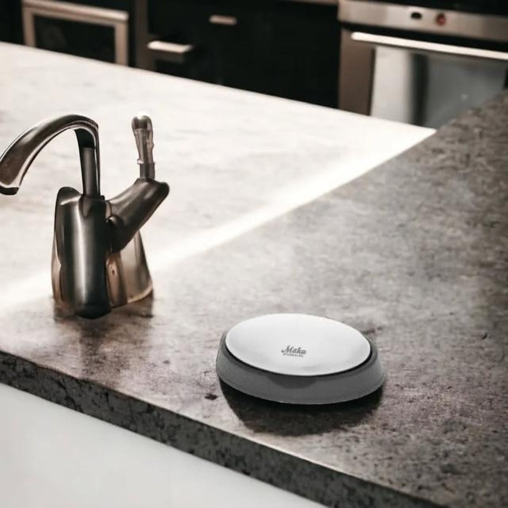 aelgmark stainless steel odor removing soap with grey base on kitchen counter next to faucet.