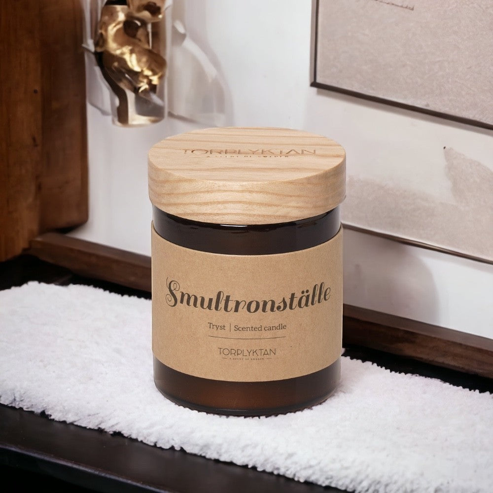 aelgmark北歐生活選物: Torplyktan amber glass scented candle with wooden lid, featuring a kraft paper label with 'Smultronställe' and 'Trygt | Scented candle'.