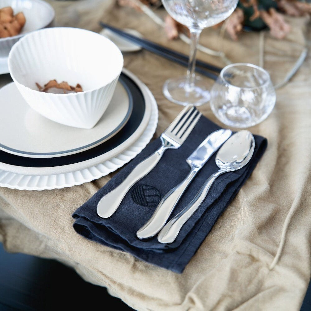 aelgmark Waverly 16-piece stainless steel cutlery set with wave-inspired design on dark blue napkin.