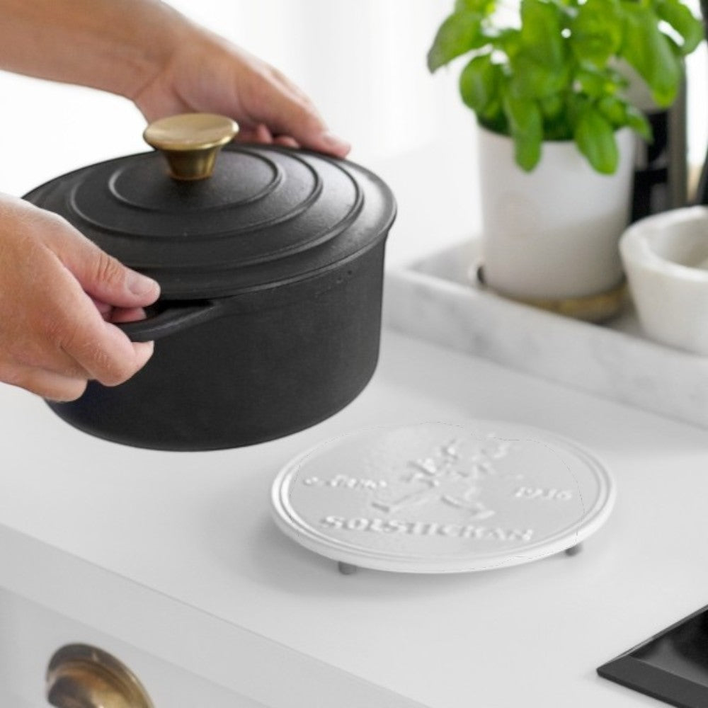aelgmark北歐生活選物 white cast iron trivet with embossed SOLSTICKAN 1936 boy motif, protecting surfaces from hot pots.