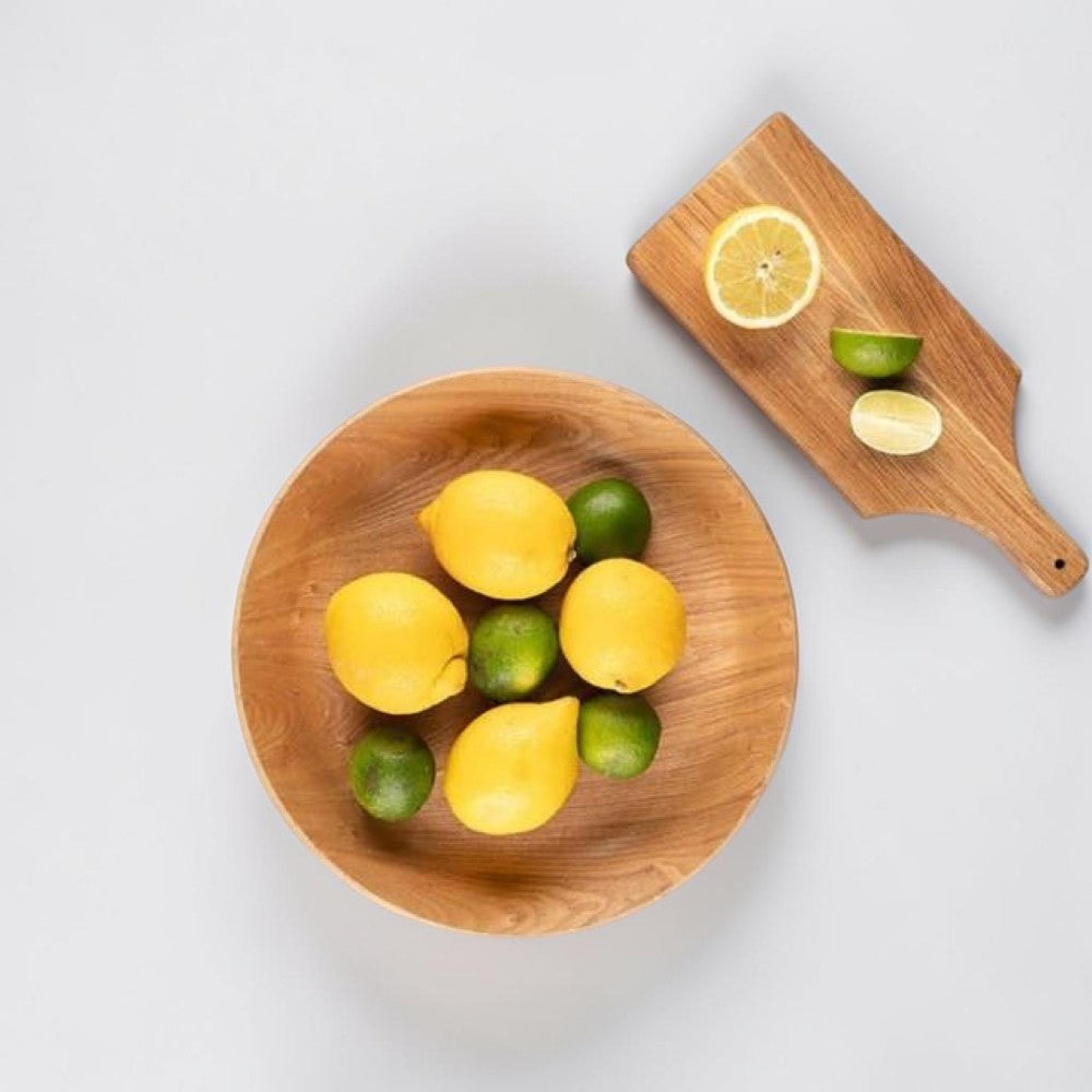 aelgmark wooden serving bowl with lemons and limes, and a wooden cutting board with citrus slices.